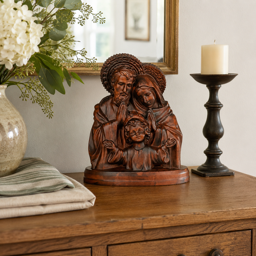 Hand-carved wooden Holy Family statue of Jesus, Mary and Joseph on a sideboard beside a candle