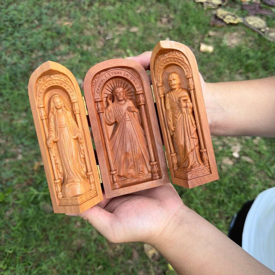 Travel altar triptych open in two hands — Our Lady, Divine Mercy, and St. Joseph