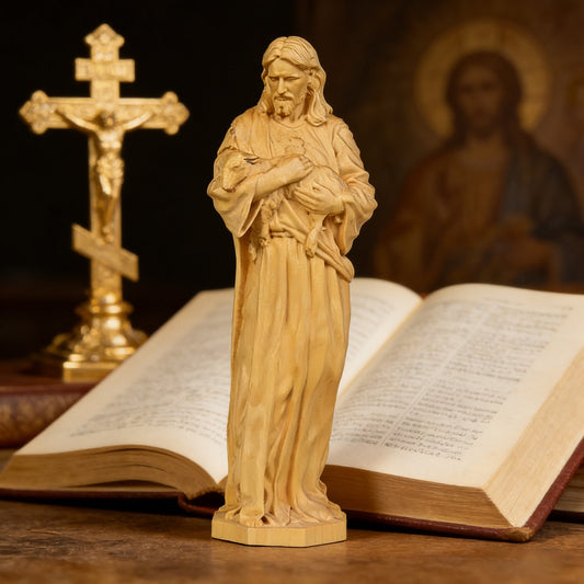 The Good Shepherd statue in pale boxwood beside an open bible and crucifix