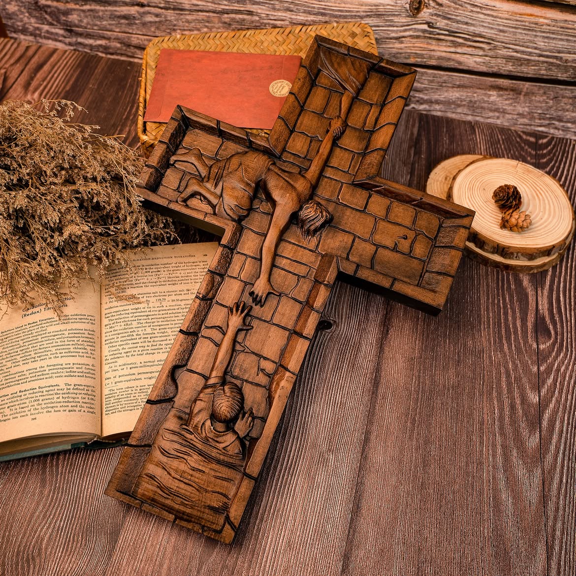 The Savior Cross lying on a rustic wooden table beside an open book, showing the depth of the carved relief