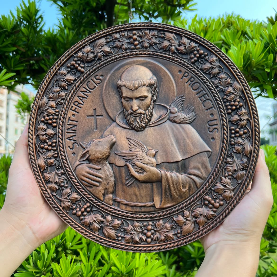 St. Francis medallion held in two hands outdoors